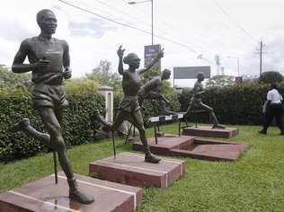 Segurança caminha ao redor de estátuas que homenageiam grandes fundistas quenianos, na sede da federação de atletismo, em Nairóbi